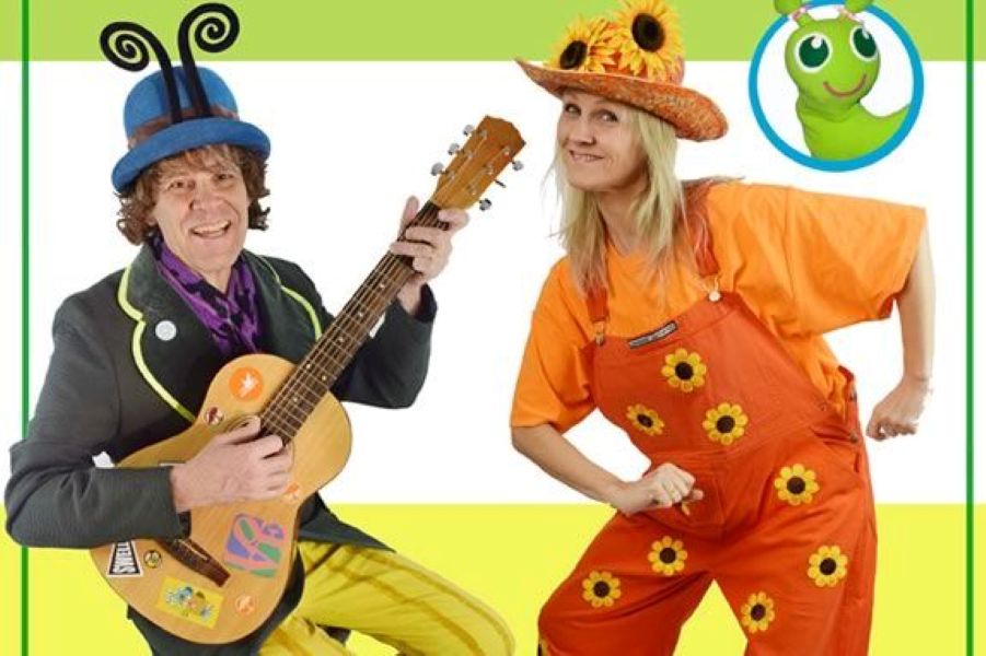 Musician with guitar and woman dressed in orange, dancing.