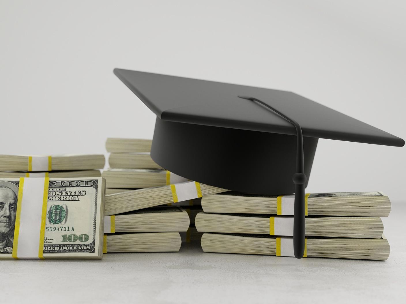 graduation cap on top of stacks of money